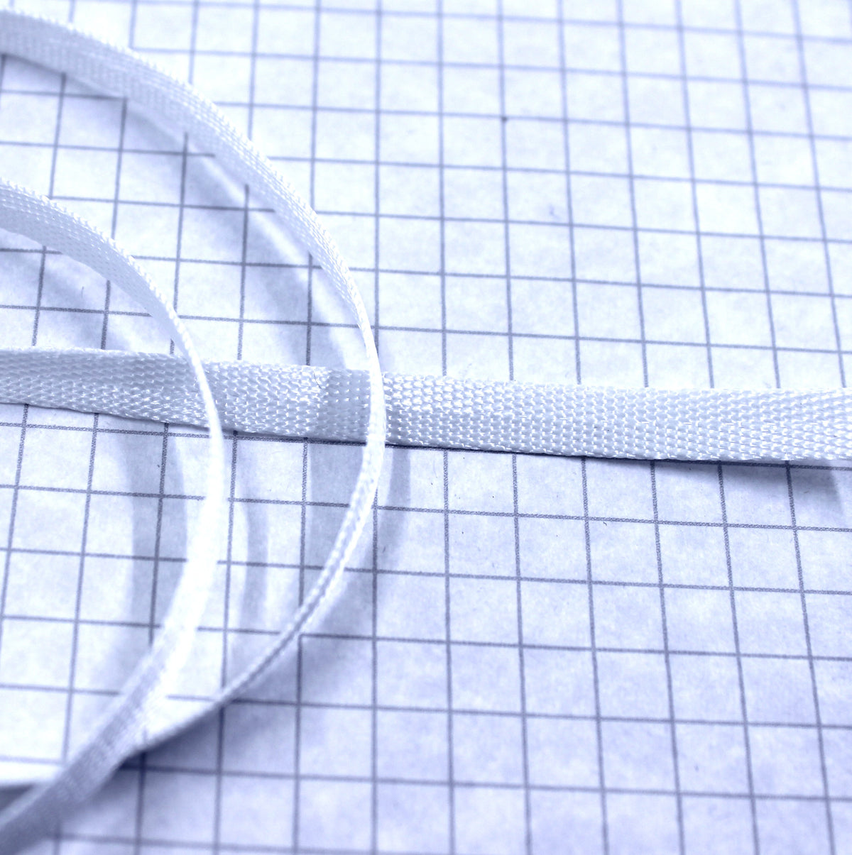 White 1/4-inch nylon twill tape, woven flat with loose lengths.