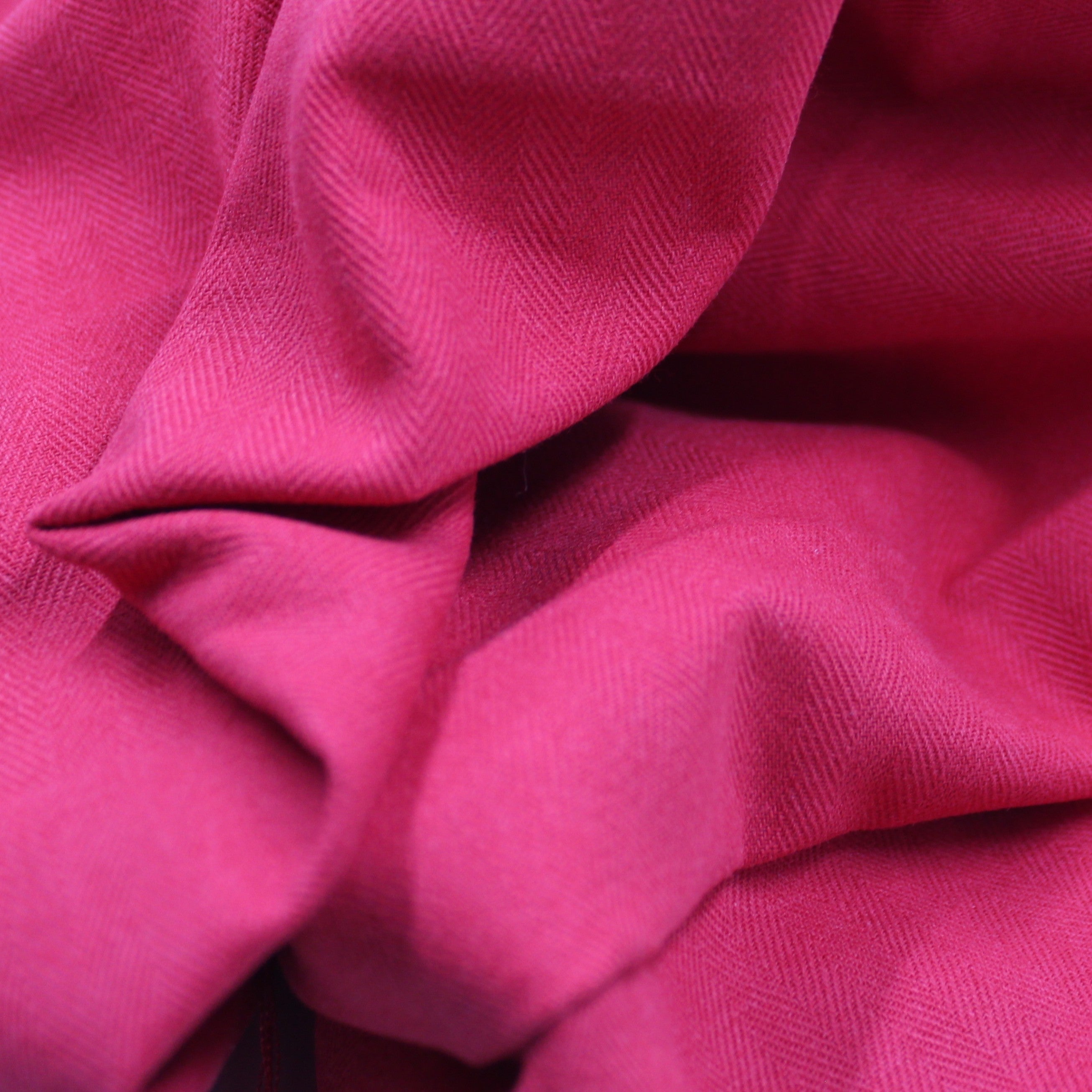 Fuchsia herringbone coutil fabric, folded with fine diagonal texture