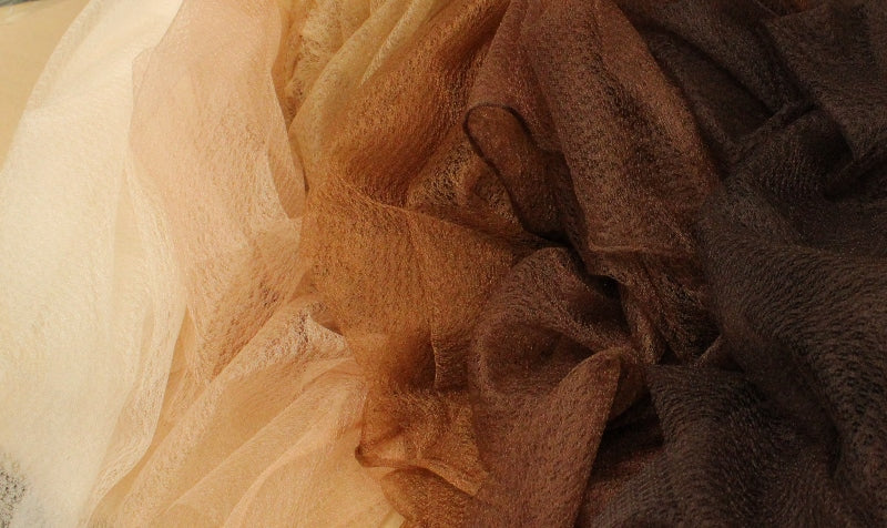 A pile of soufle fabric, The deepest, darkest brown is on the far right